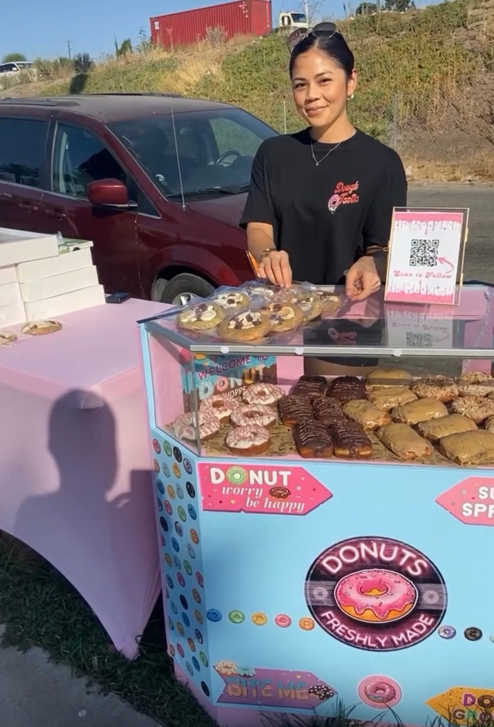 Ashley at the Stufft donut stand with a case of fresh donuts and cookies